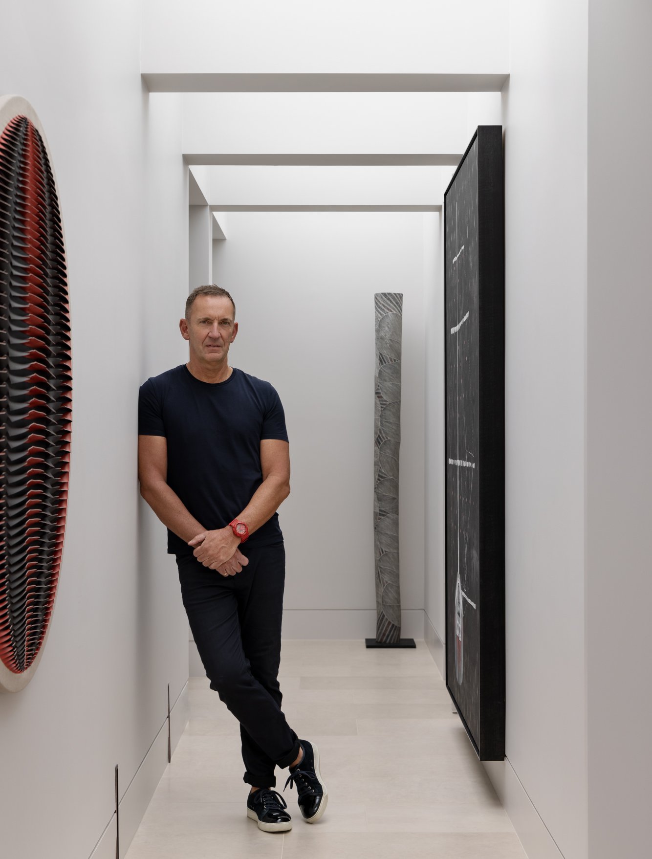 Architect Philip Mathieson in the upstairs hallway of Kurraba Penthouse, featuring artworks by Marion Borgelt, Kirra&nbsp;Jamison and Malaluba Gumana, 2023. Photo: Tim Kaye.